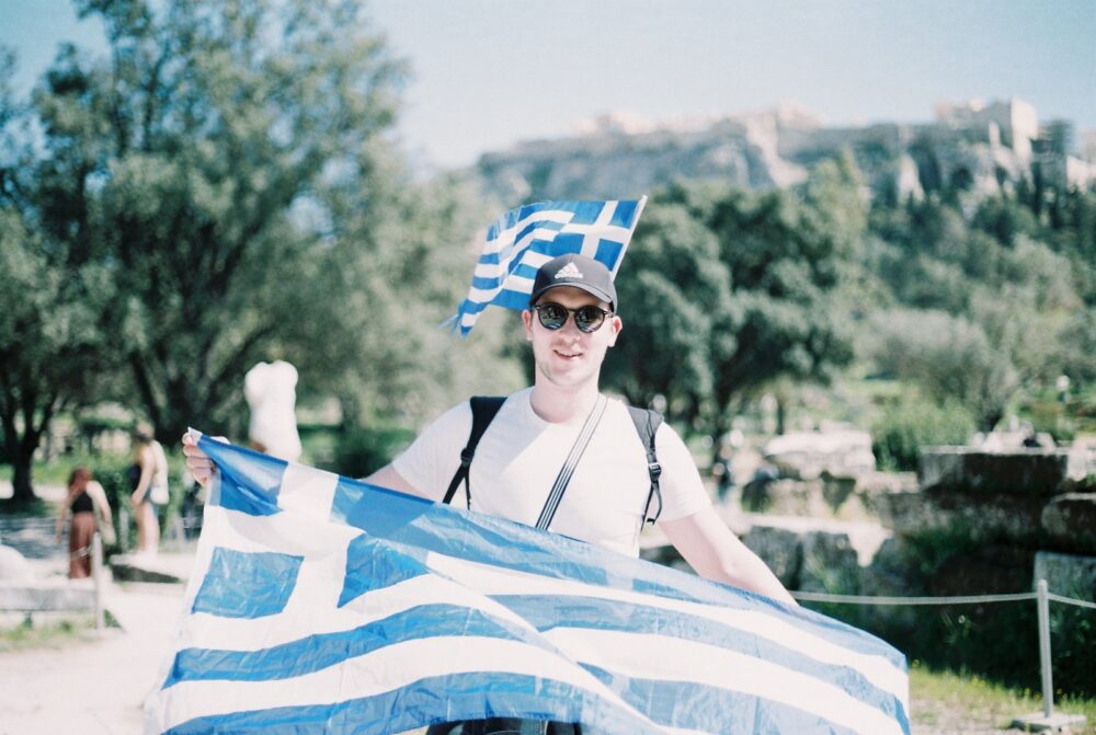 greek kamaki, Young Man in Sunglasses Holding a Greek Flag